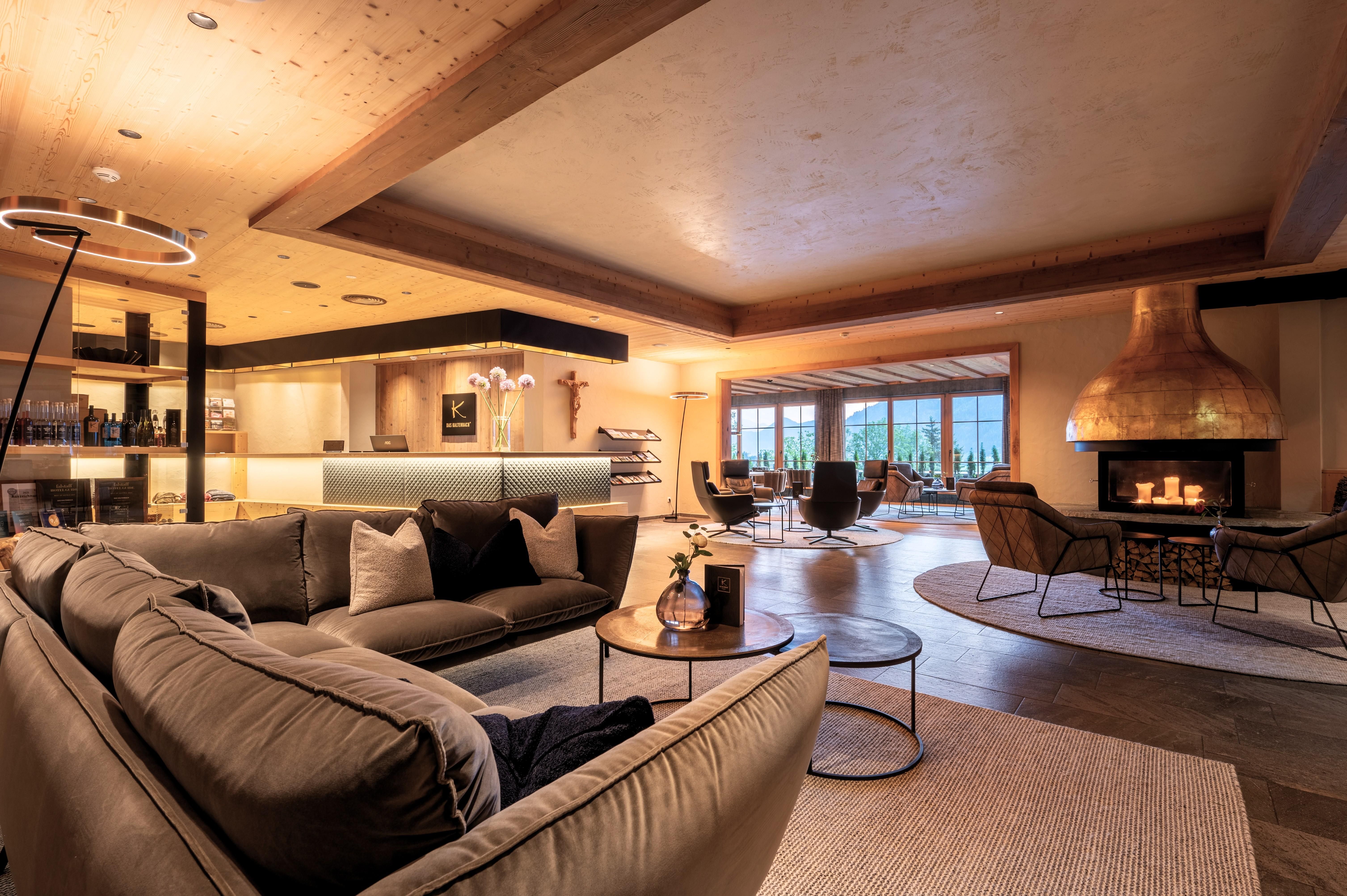 A stylish living space with a comfortable sofa, a coffee table, and a modern fireplace. Large windows offer a view of the landscape and provide plenty of light.