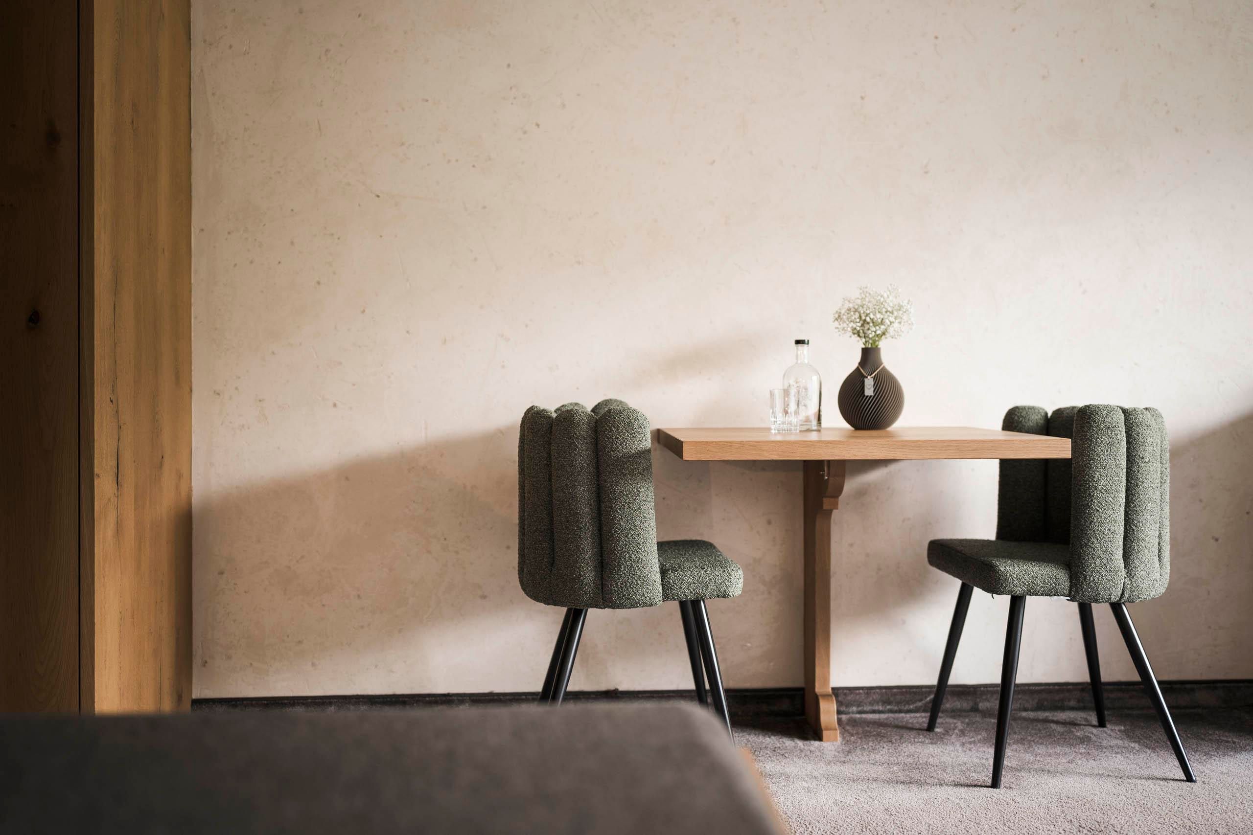An elegant table with two chairs in a modern room. A vase with flowers and a water bottle decorate the table.
