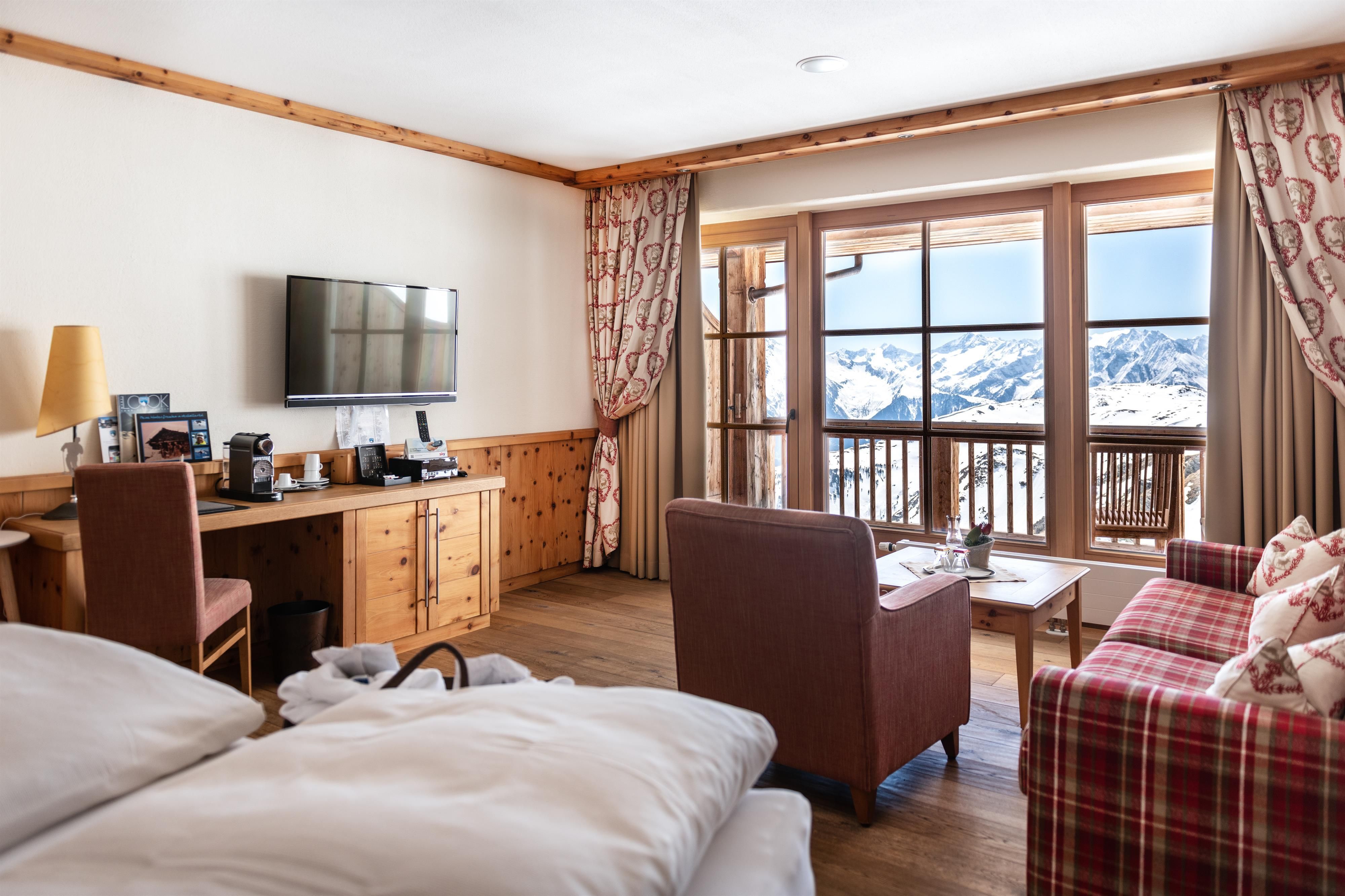 A cozy hotel room with wood decor and a television.
Large windows offer a view of the mountains.