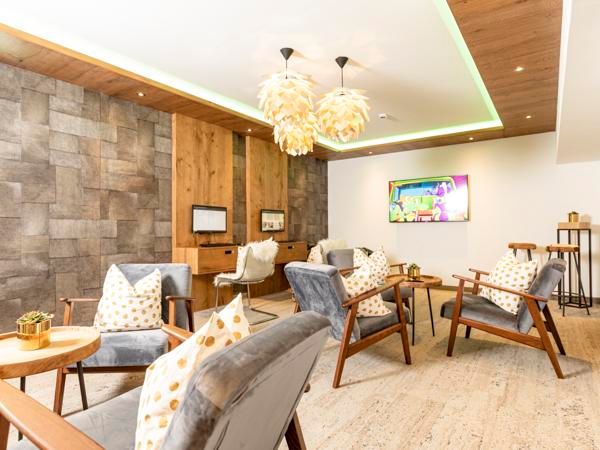 A modern room with comfortable armchairs and a warm wood design. Soft lighting and a television create an inviting atmosphere.