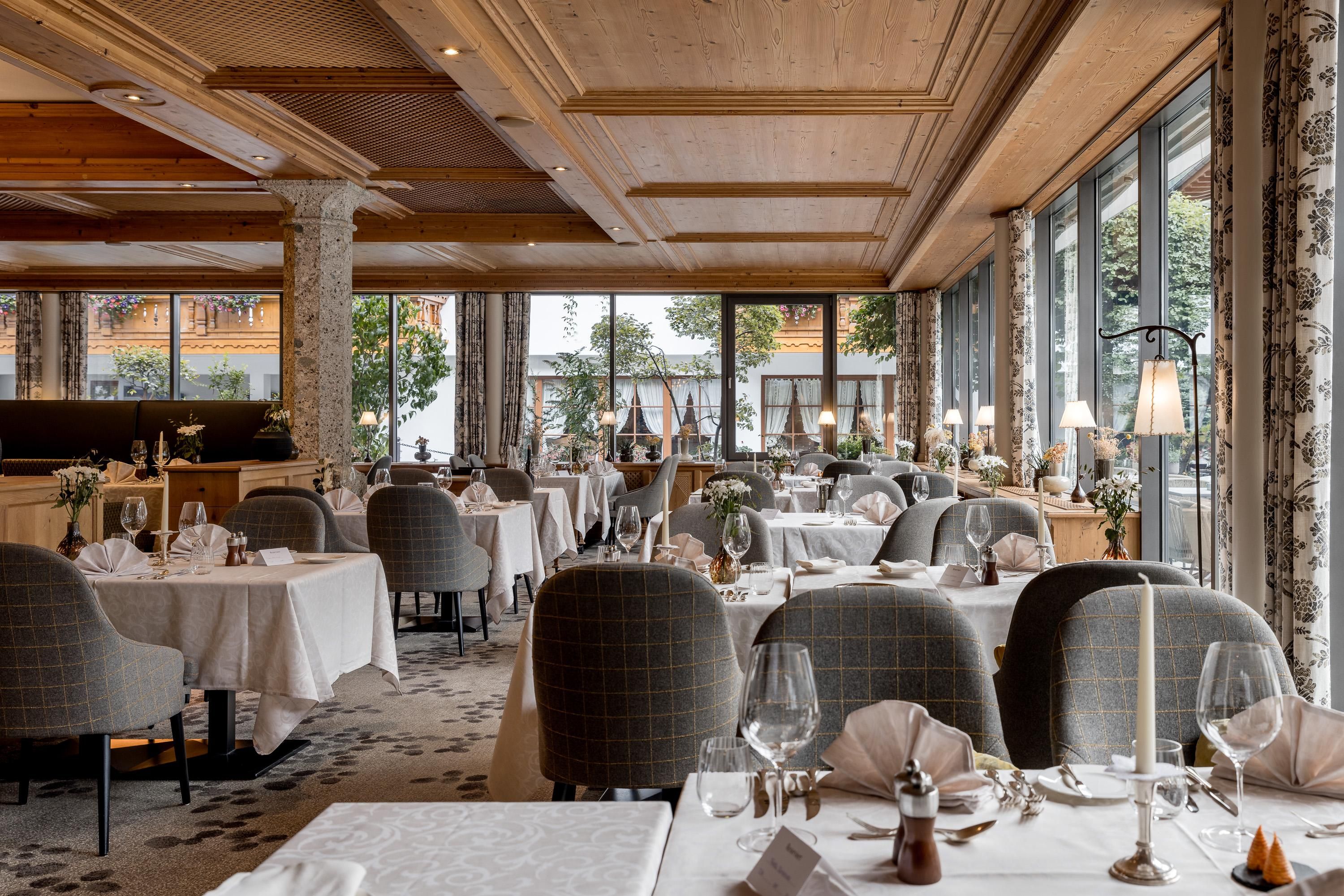 An elegant restaurant with tastefully set tables and a cozy atmosphere. Large windows provide a view of the surroundings.