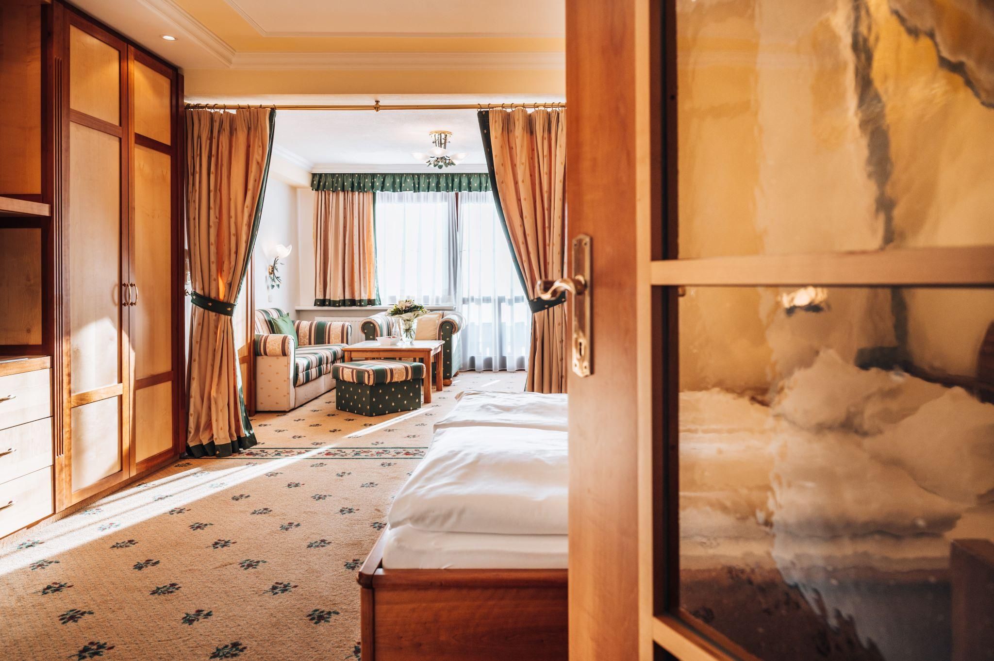 A stylish room with a cozy bed and an inviting seating area. Large windows let in plenty of light and create a pleasant atmosphere.