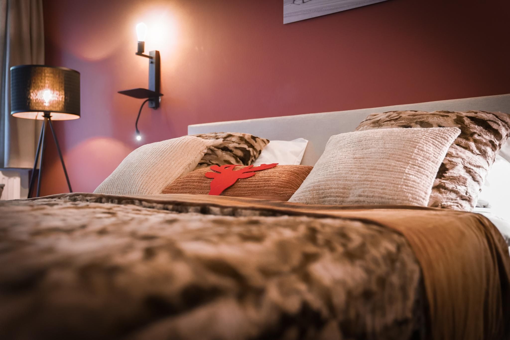 A cozy bedroom with a stylish bed and decorative pillows. An elegant lamp provides warm light and an inviting atmosphere.