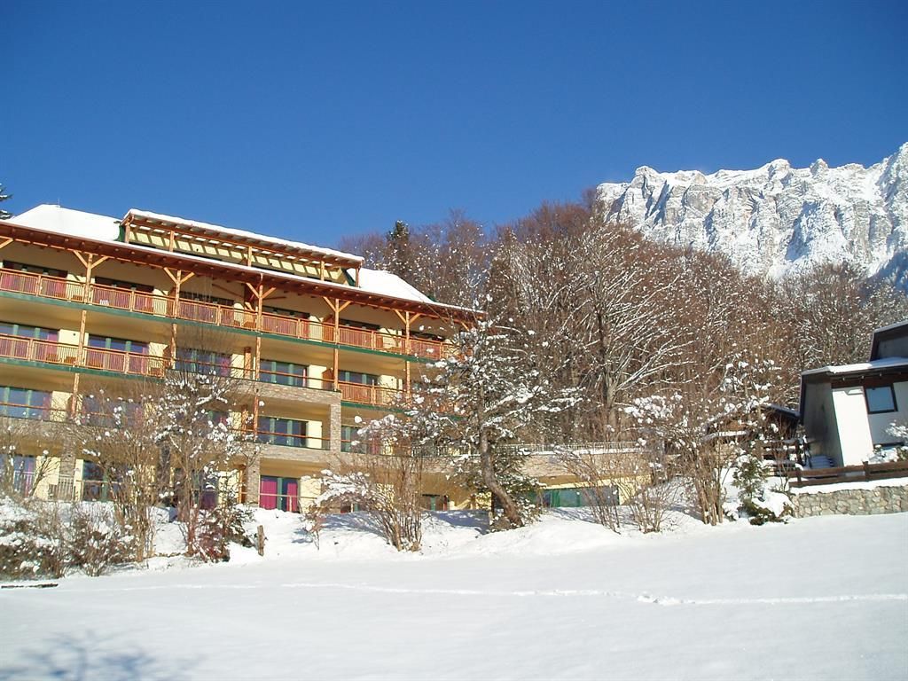 A cozy hotel building amidst a snowy landscape. In the background, snow-covered mountains can be seen.