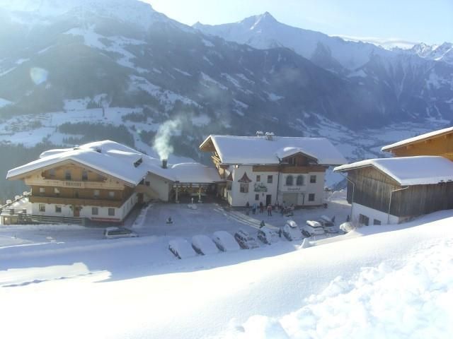 A picturesque mountain village in the snow with traditional wooden houses. The surroundings are surrounded by majestic mountains and the sun is shining clearly in the sky.