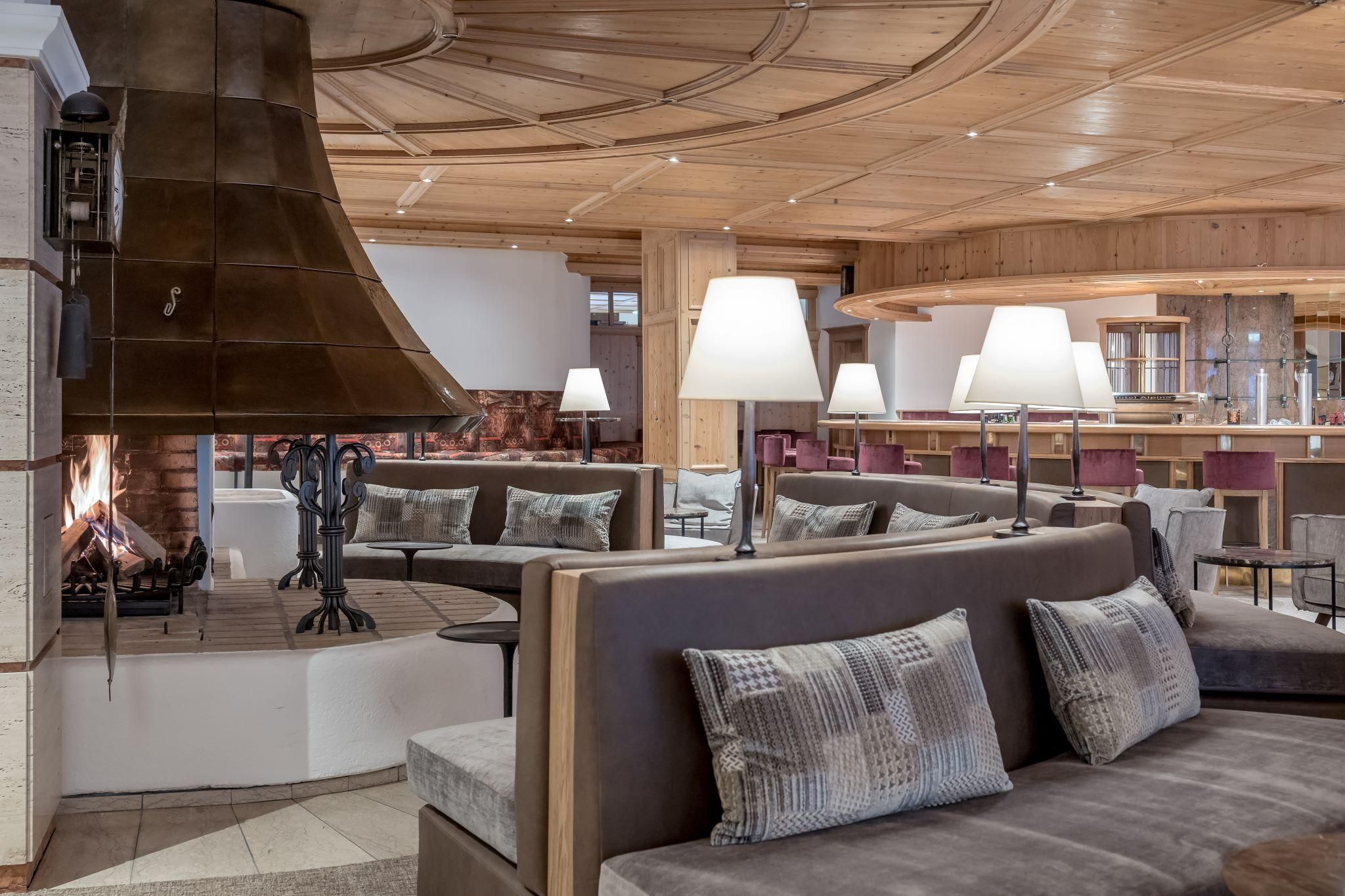 A cozy interior with a modern seating area and a fireplace. The room features wooden elements and soft lighting that create an inviting atmosphere.