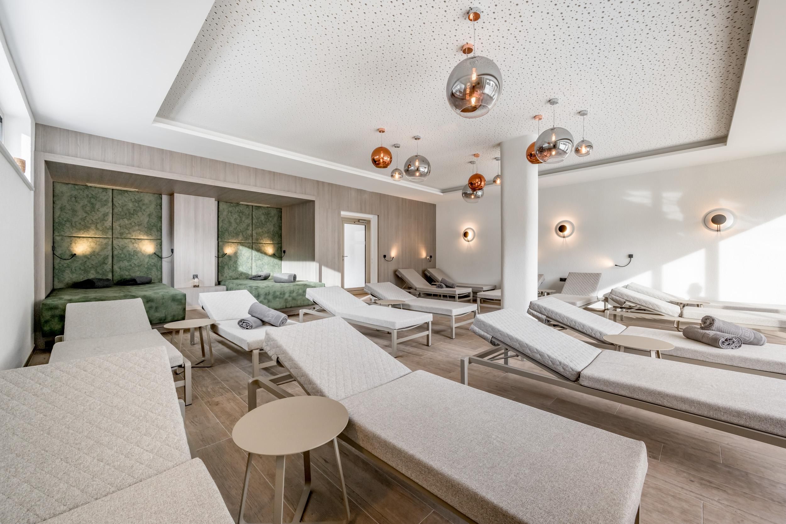 A modern relaxation room with loungers and elegant lighting. The atmosphere is calm and inviting.