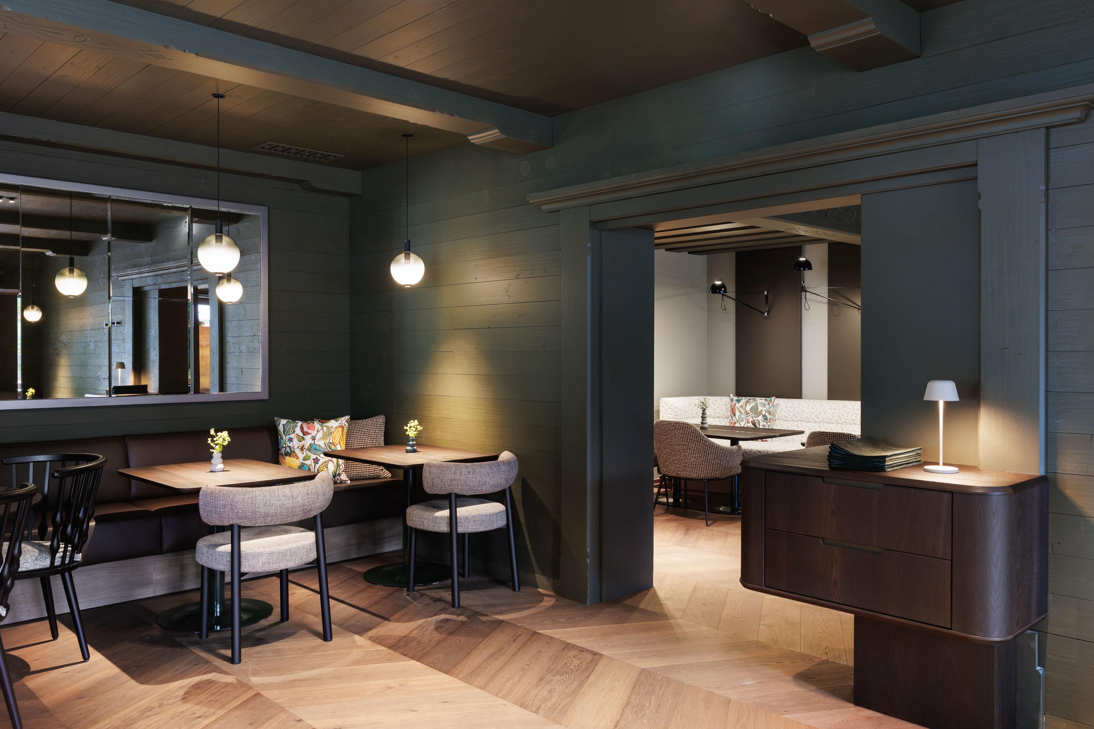 An elegant interior with wooden floors and a cozy atmosphere. There are tables, chairs, and soft lighting, perfect for relaxed meetings.