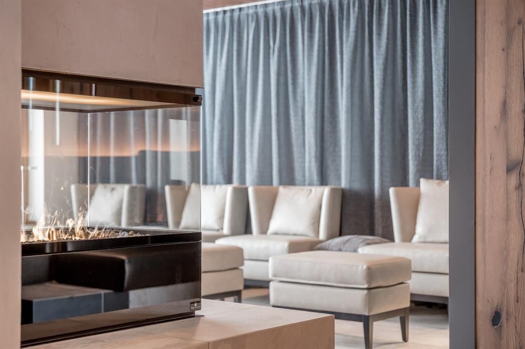 A modern living room with an elegant fireplace in the foreground. The bright sofas and the gray curtain create a cozy atmosphere.