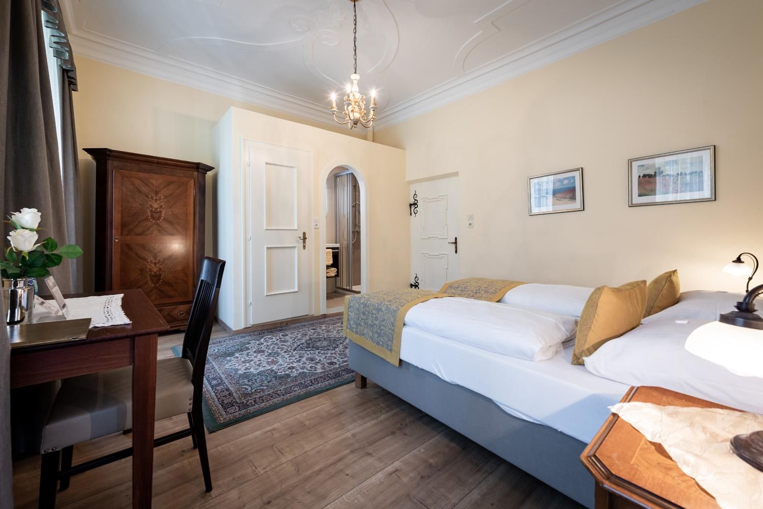 A cozy bedroom with a comfortable bed and warm colors. The room is bright and stylish, furnished with a table and a wardrobe.