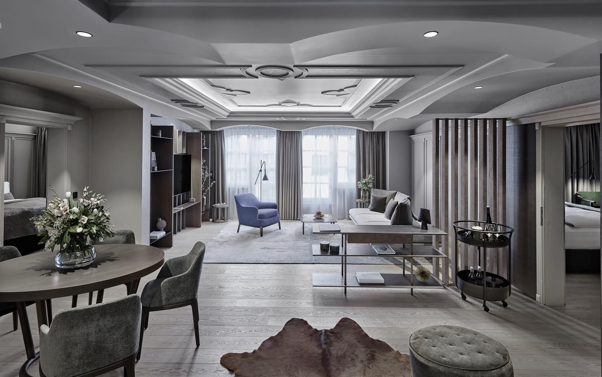 A stylish, modern suite with an elegant living area and large windows. The room is bright and inviting, featuring tasteful furnishings and decorative elements.