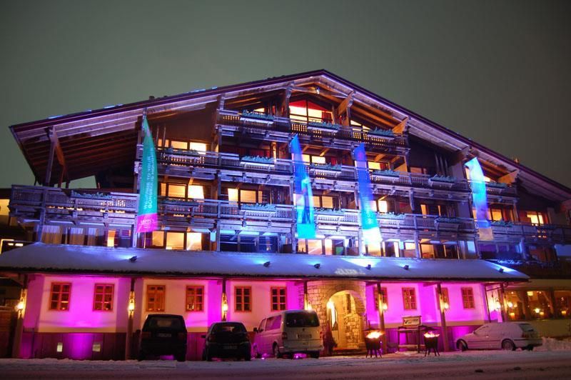 An impressive hotel building, illuminated in vibrant colors. The snow in front of the building enhances the wintry atmosphere.