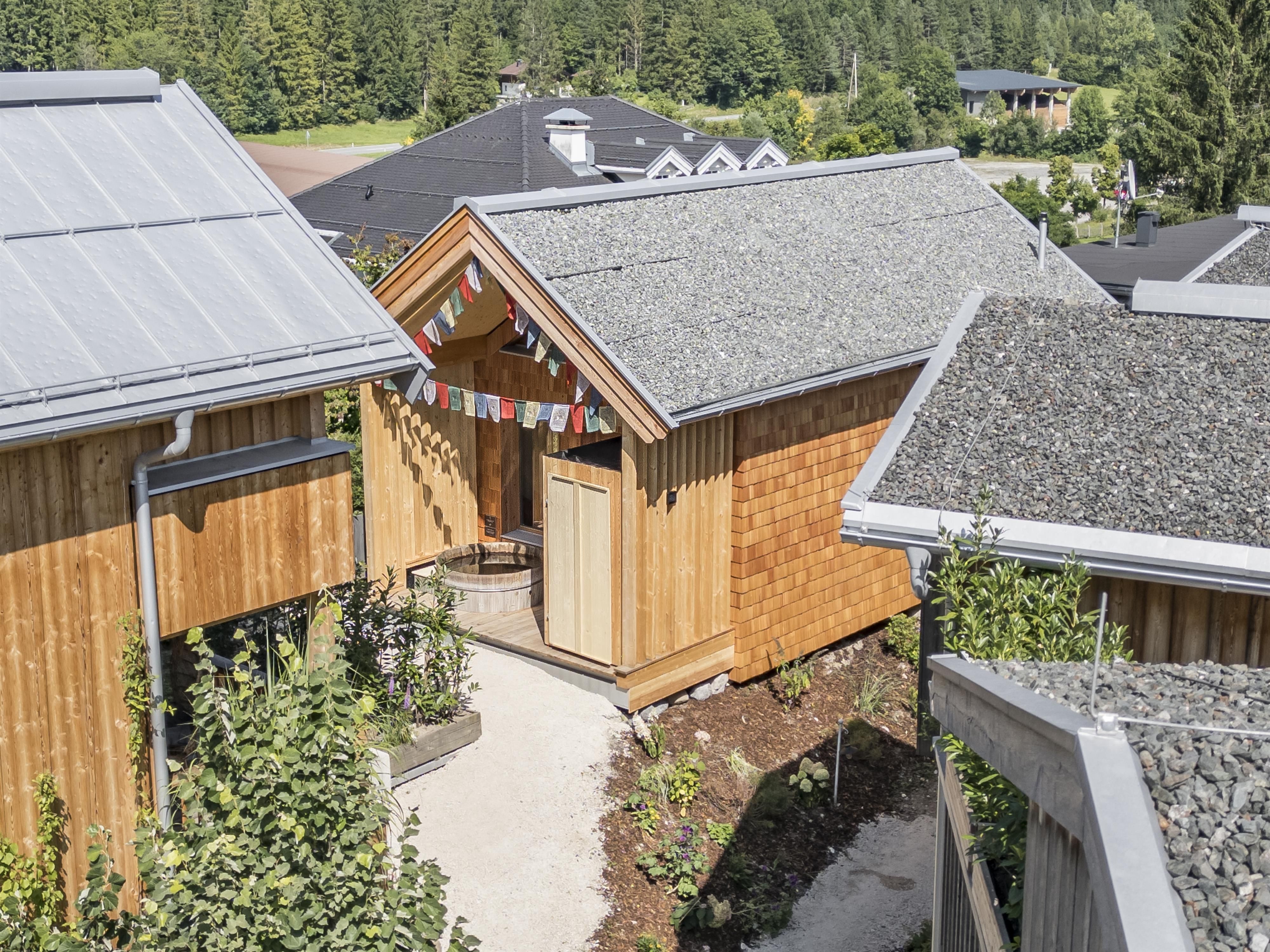 A series of modern wooden houses with sloping roofs. Colorful flags adorn the entrance and surrounding trees give the environment an inviting character.