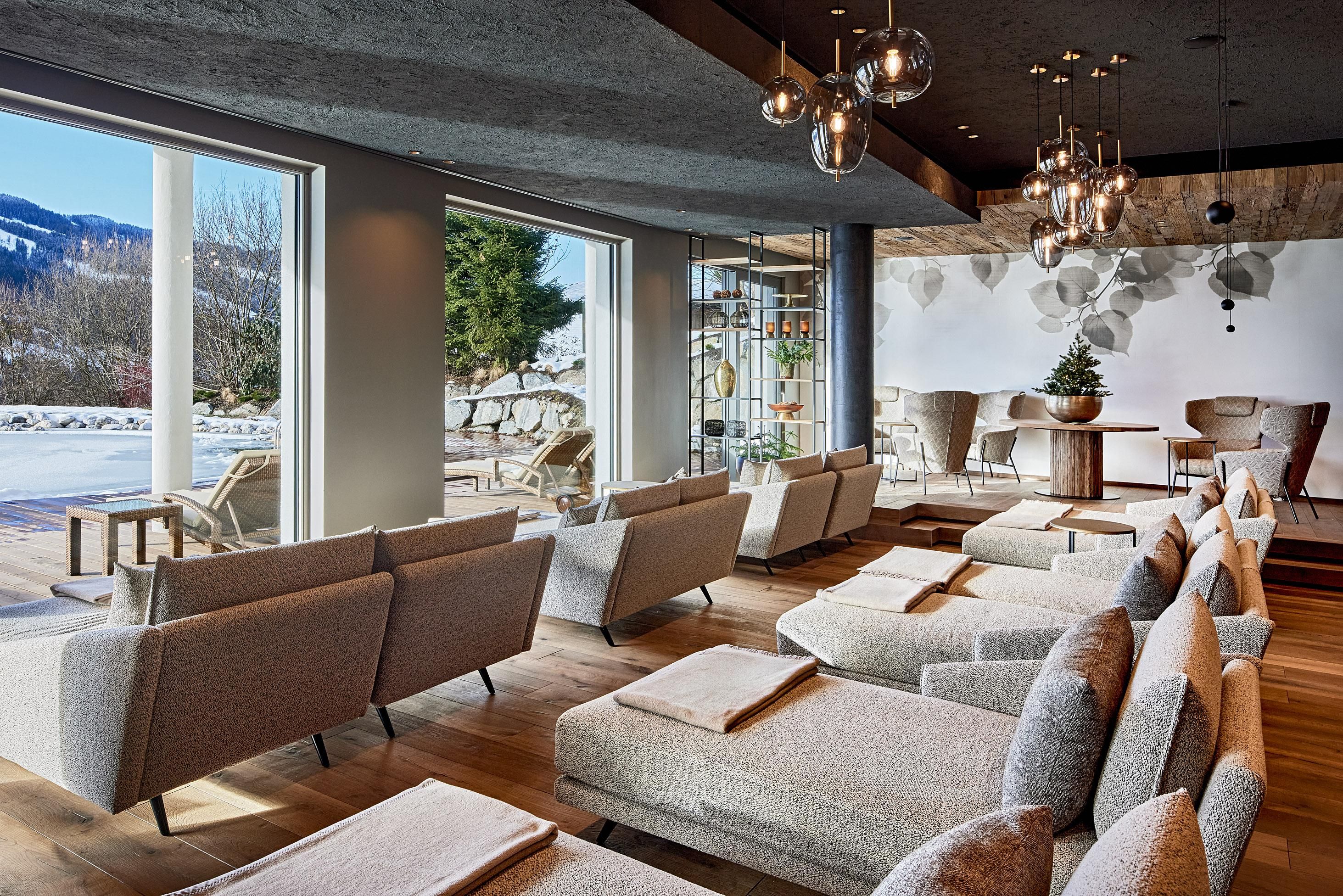 A modern living room with comfortable sofas and large windows that offer a view of nature. The decor is stylish and inviting.