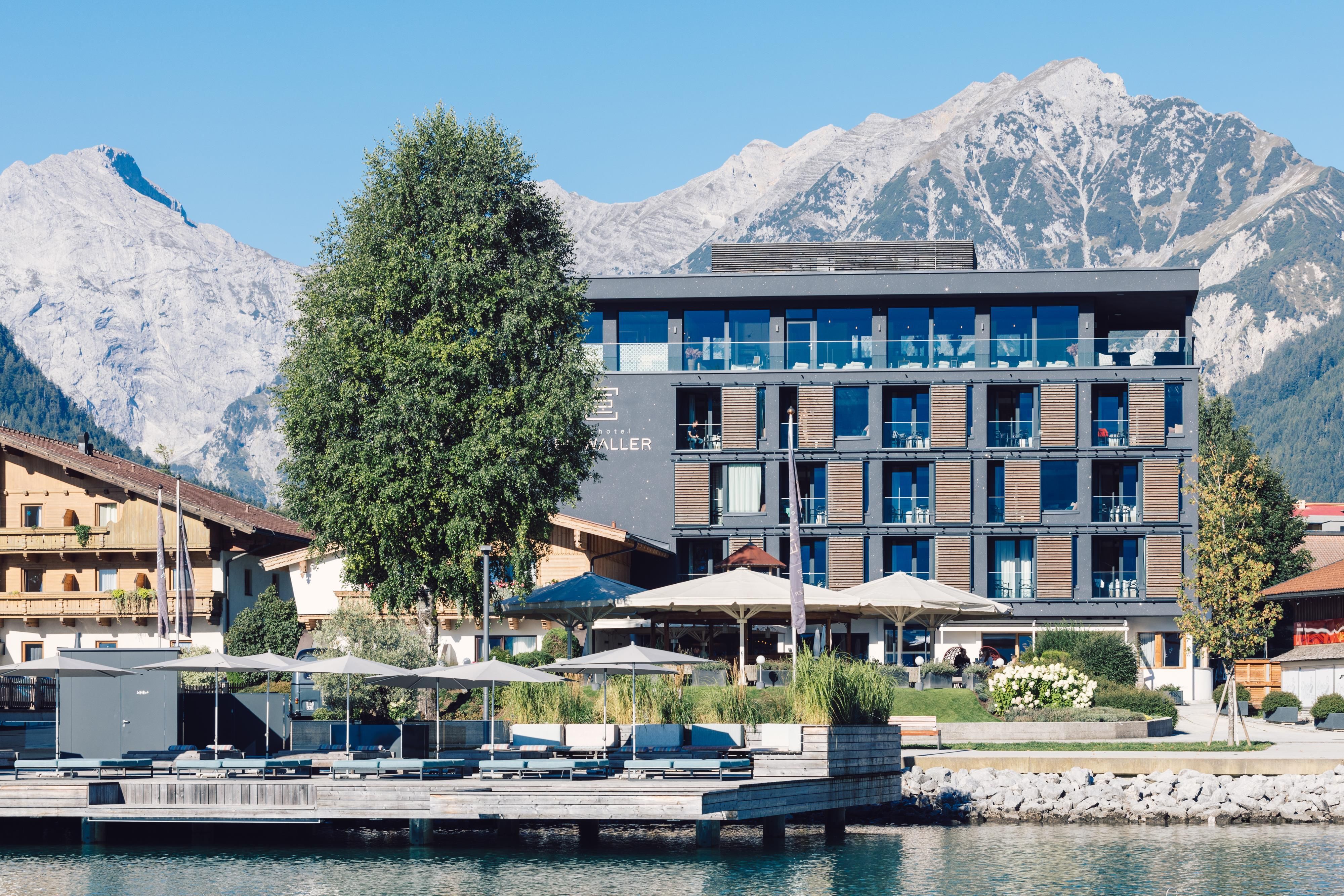 A modern hotel by the water, surrounded by mountains. The atmosphere is calm and inviting.