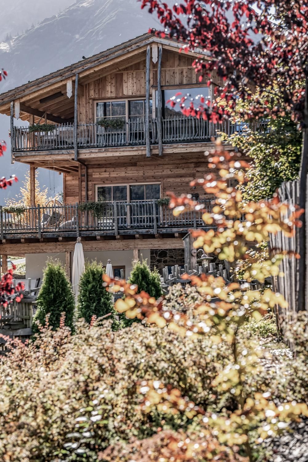A beautiful chalet with several balconies and a well-maintained garden. Colorful plants and trees surround the accommodation, creating an inviting atmosphere.