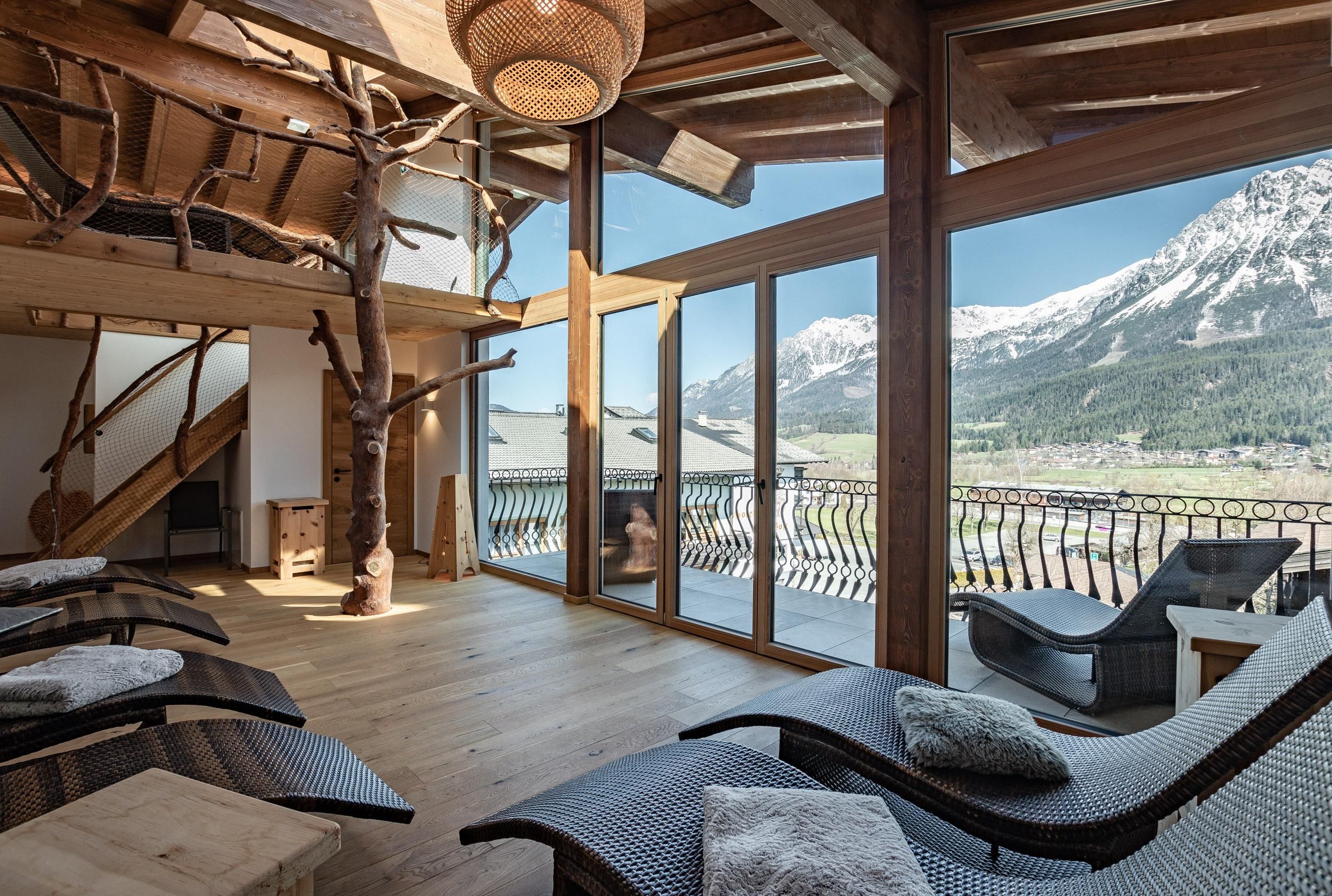 A modern relaxation room with large windows and a view of the mountains. The decor consists of comfortable loungers and natural materials.