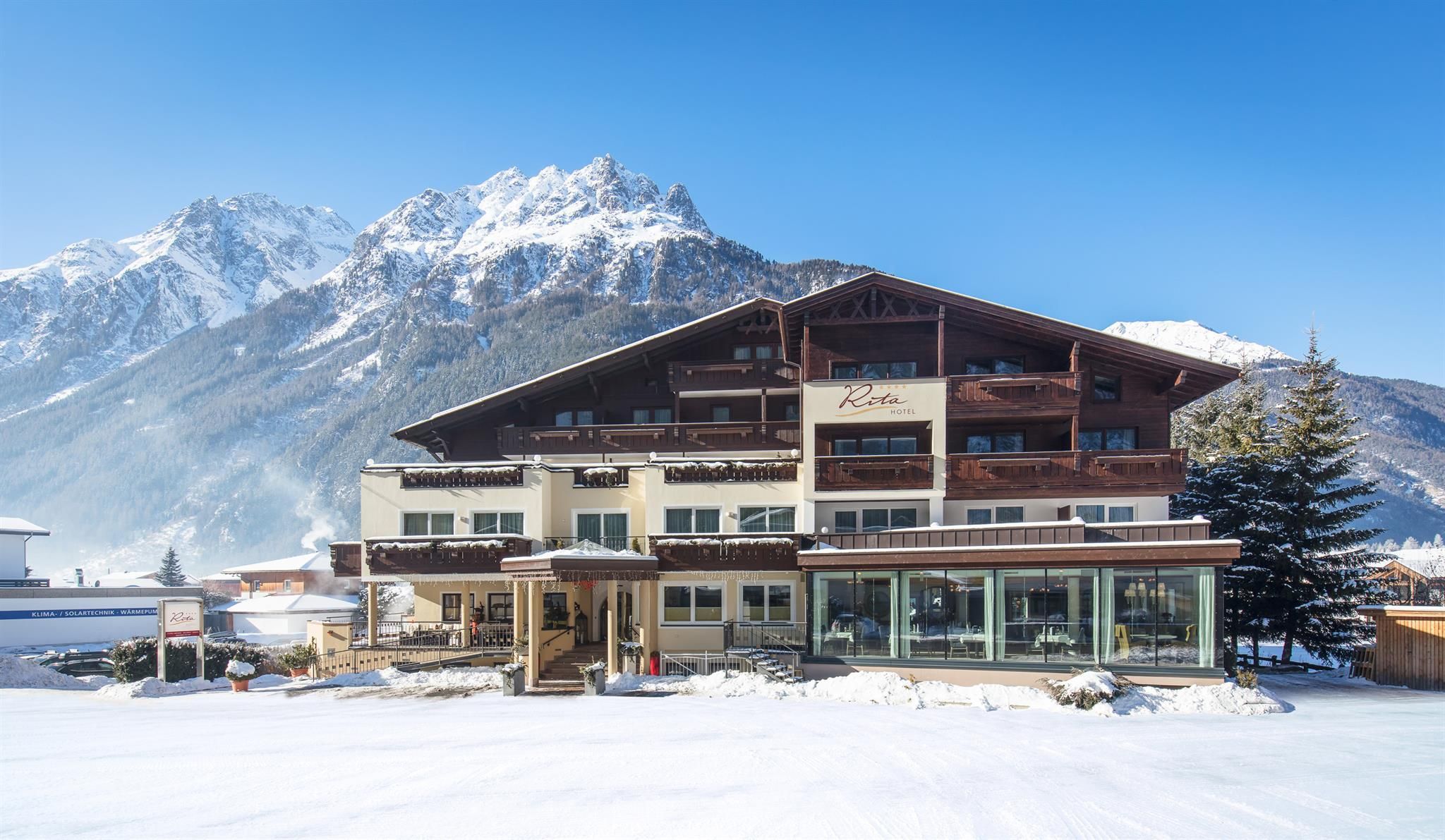 A modern hotel in the snowy mountain landscape. In the background, majestic mountains and clear blue sky can be seen.