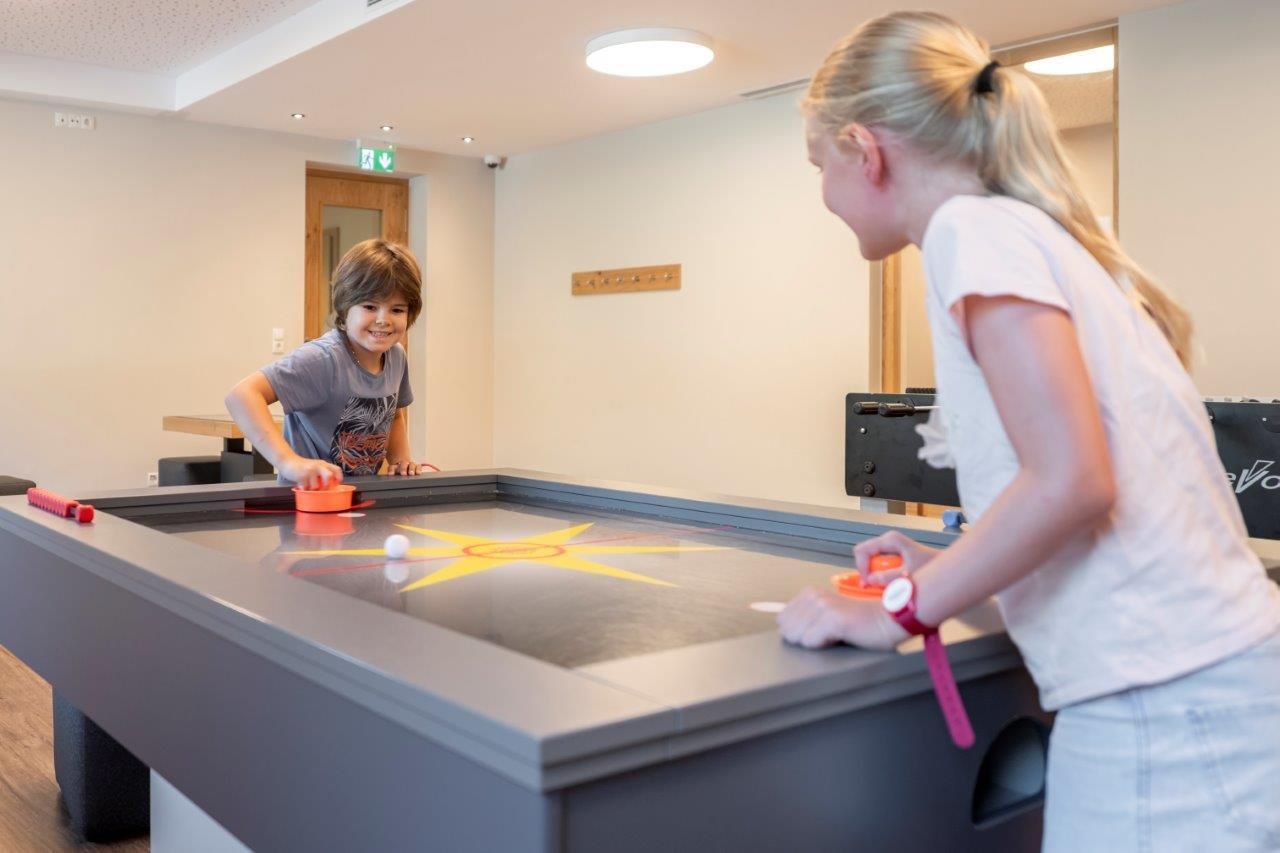 Two children are enthusiastically playing at a tabletop game. The room is bright and cheerful, perfect for fun and play.