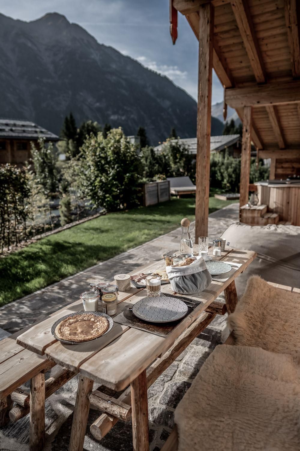 A set table outdoors with mountains in the background. The atmosphere is cozy and inviting, ideal for a breakfast in the green.