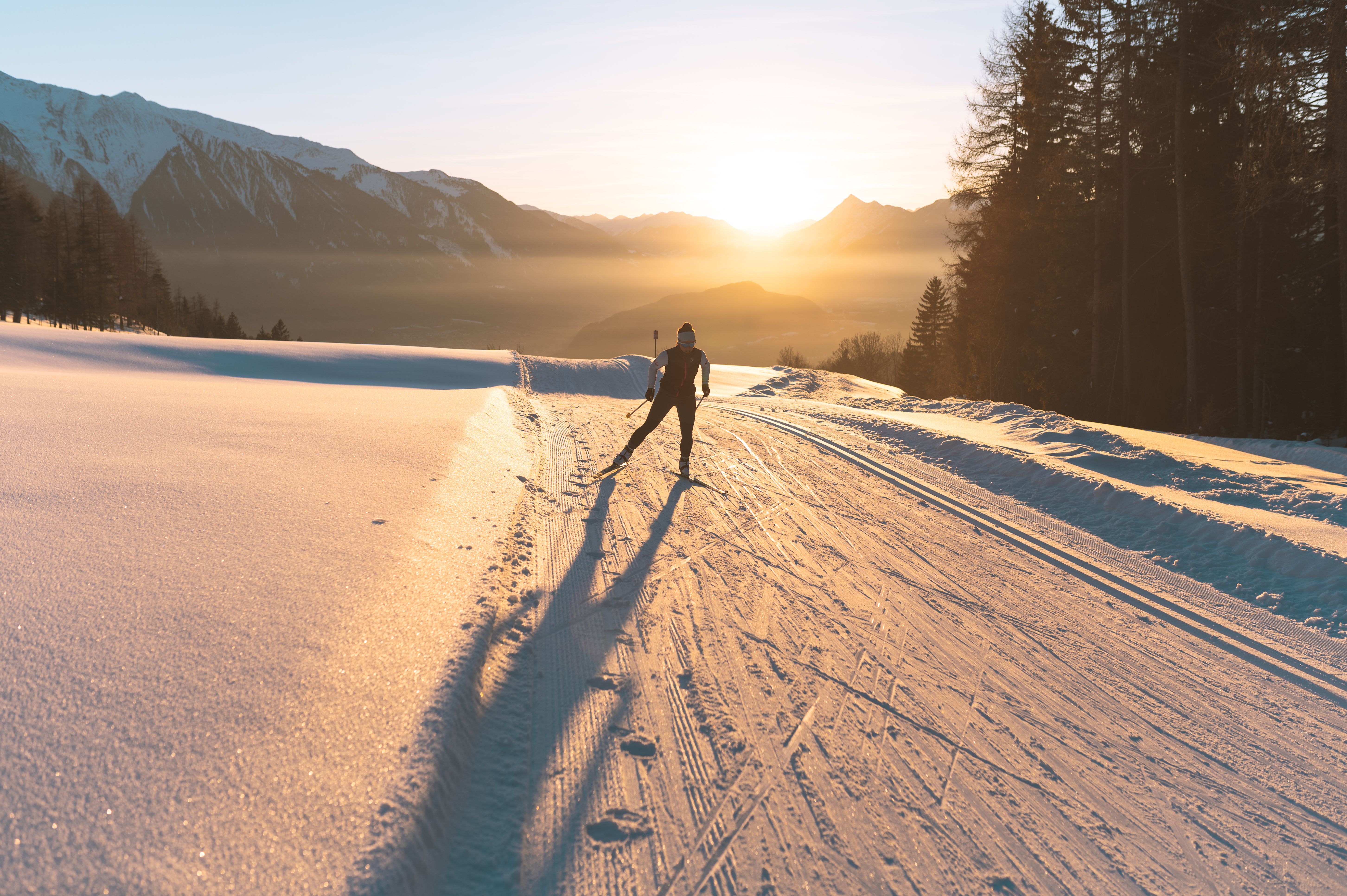 Langlaufen in Mösern bei Seefeld bei Sonnenuntergang, Langläuferin auf Loipe in untergehender Sonne