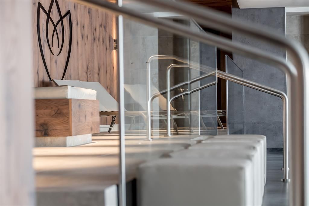 A modern interior with a minimalist design. In the foreground, a seating area and a wooden accent with a stylized logo can be seen.