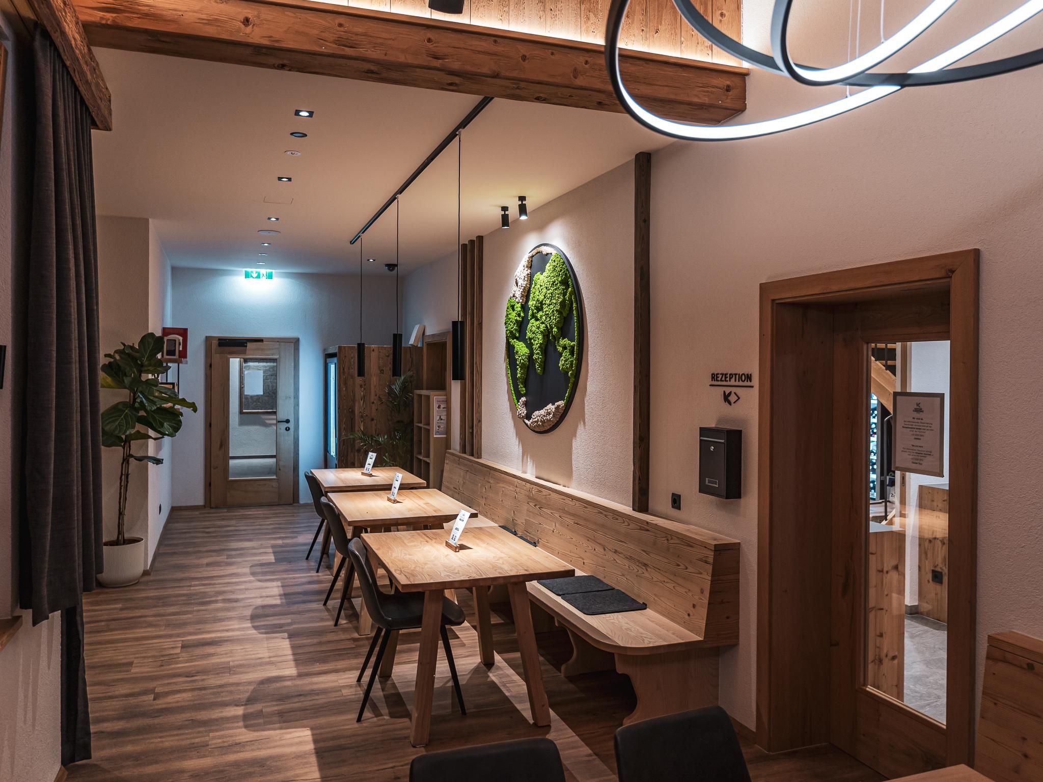 A modern restaurant with wooden details and a cozy atmosphere. On the walls are plant pictures and soft lighting.