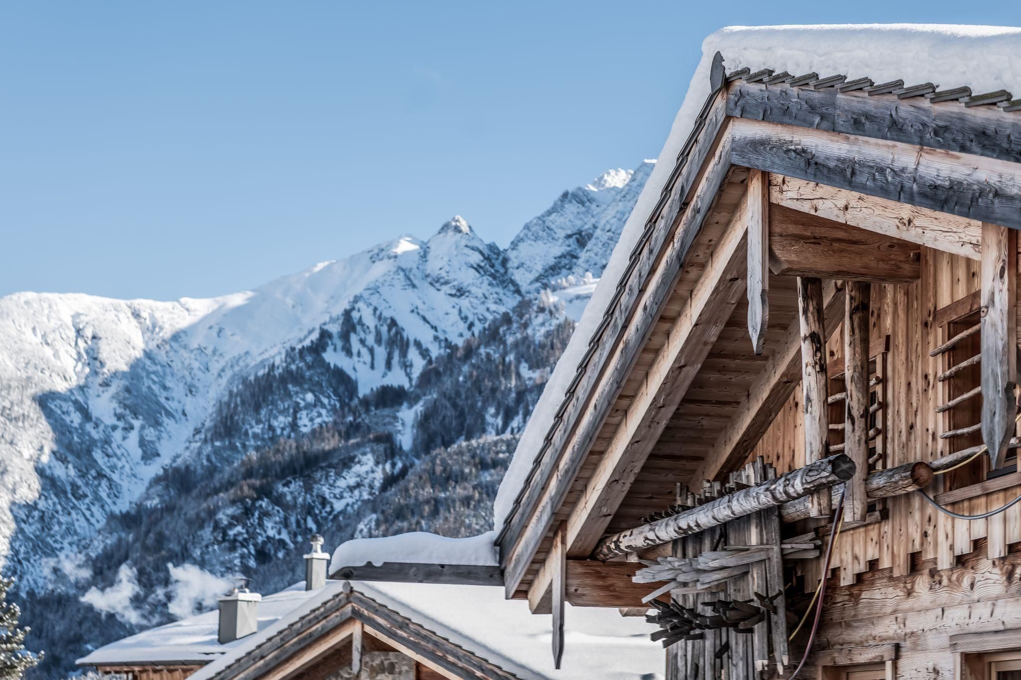 An idyllic mountain landscape with snow-covered peaks and chalets. The clear sky enhances the wintry atmosphere.