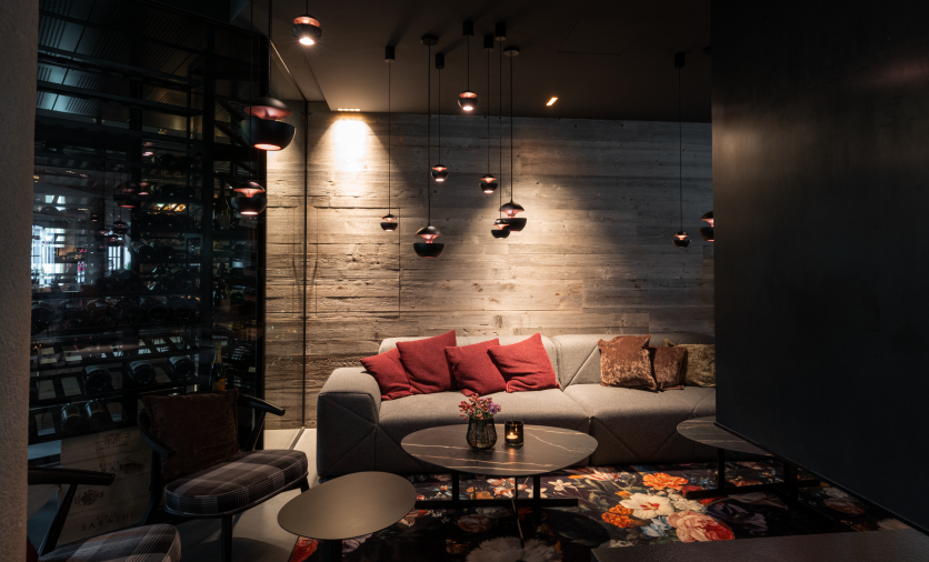 A stylish living room with a gray couch and red cushions. Soft lighting and a blooming rug create a cozy atmosphere.