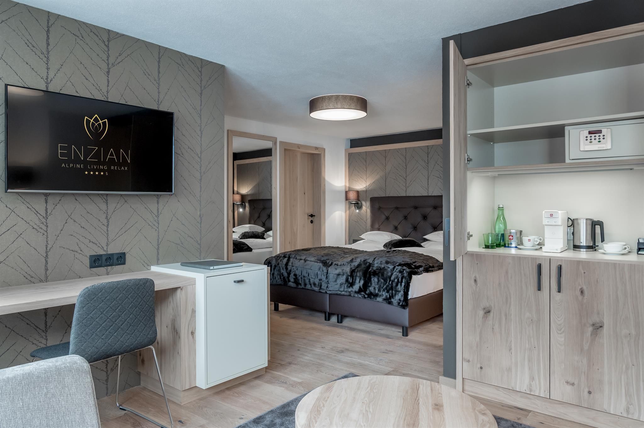 A modern room with a cozy bed, a television, and a small refrigerator. The decor is stylish and inviting.