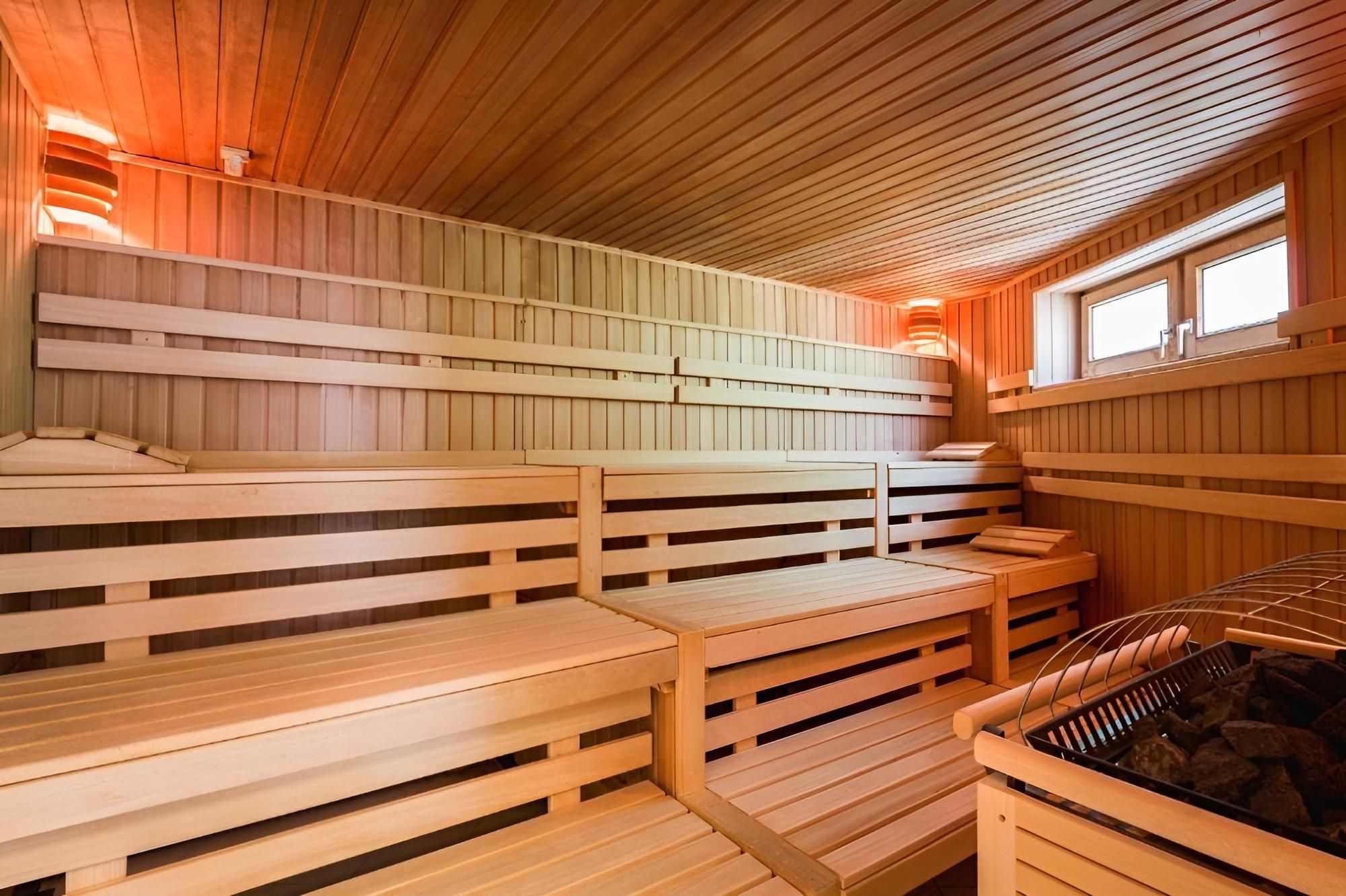 A modern sauna with wooden benches and soft lighting. The room conveys a relaxing atmosphere.