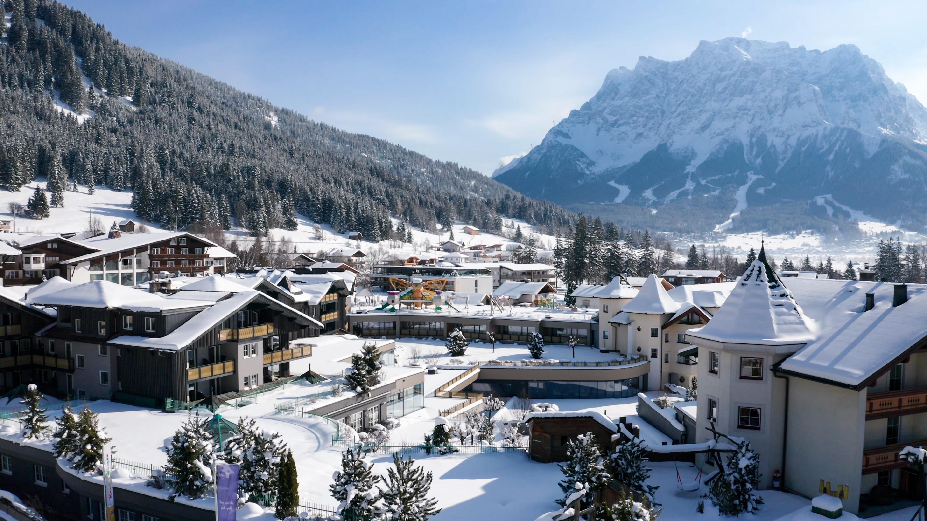 A picturesque winter landscape with snowy mountains and charming cottages. The clear sky and the snow-covered trees create a tranquil atmosphere.