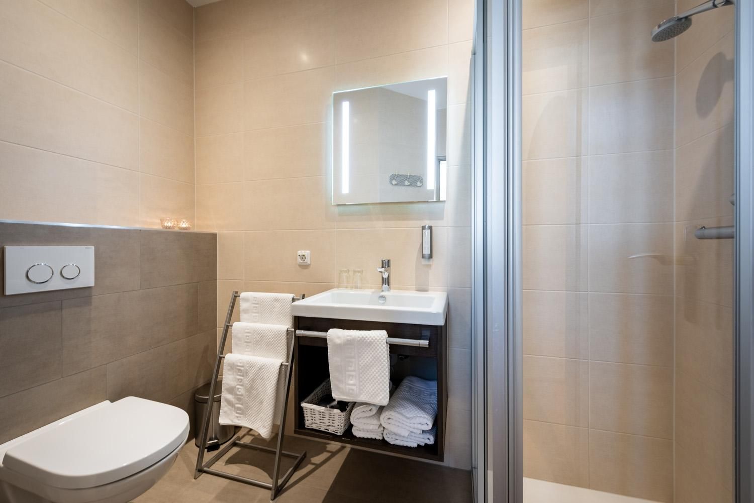 A modern bathroom with a shower, sink, and towels. It is bright and designed in a minimalist style.