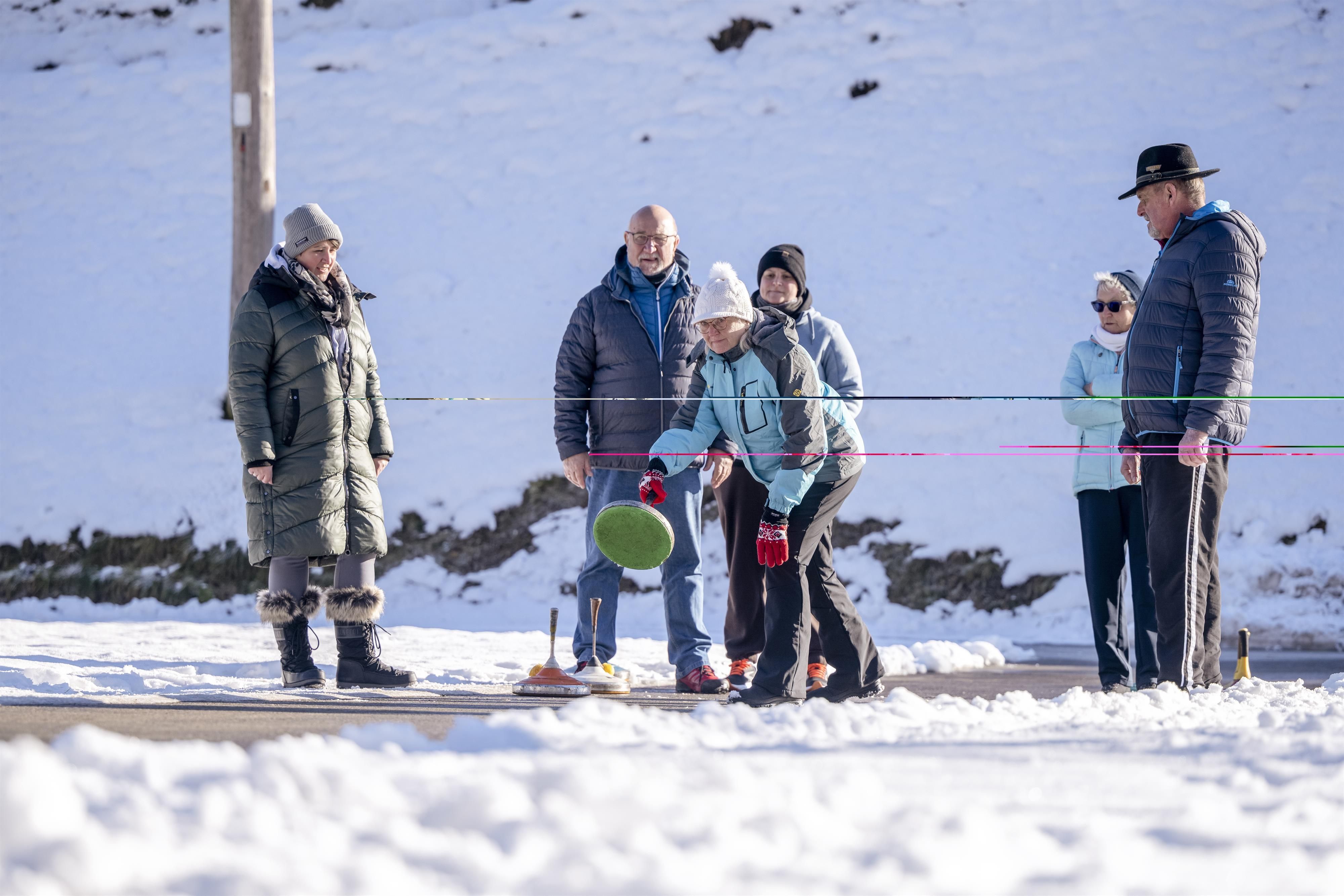 A group of people is playing in the snow. They are dressed in warm clothes and are focused on the game.