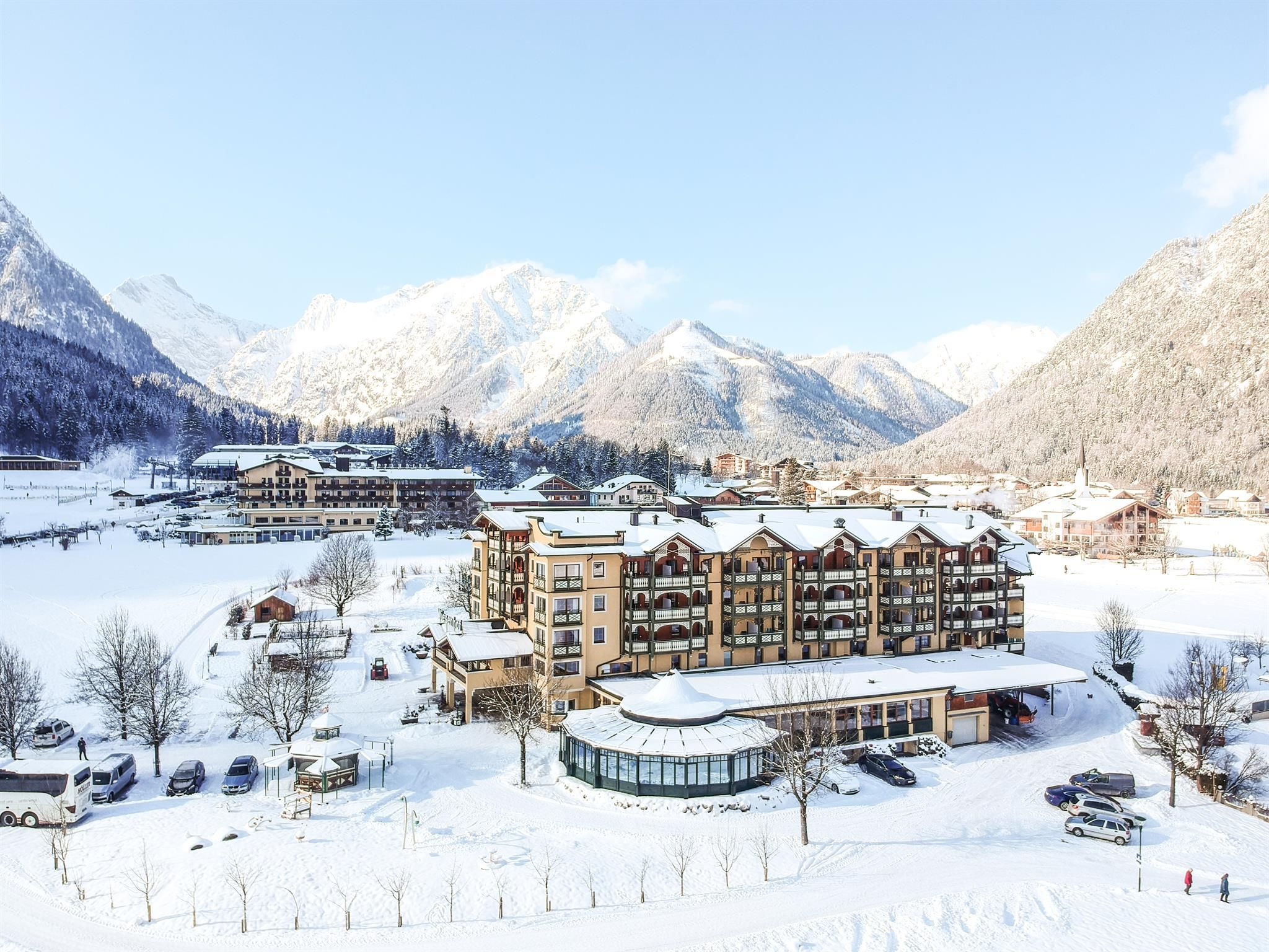 A picturesque hotel in a snowy landscape. The surrounding mountains and the clear sky create a tranquil winter atmosphere.