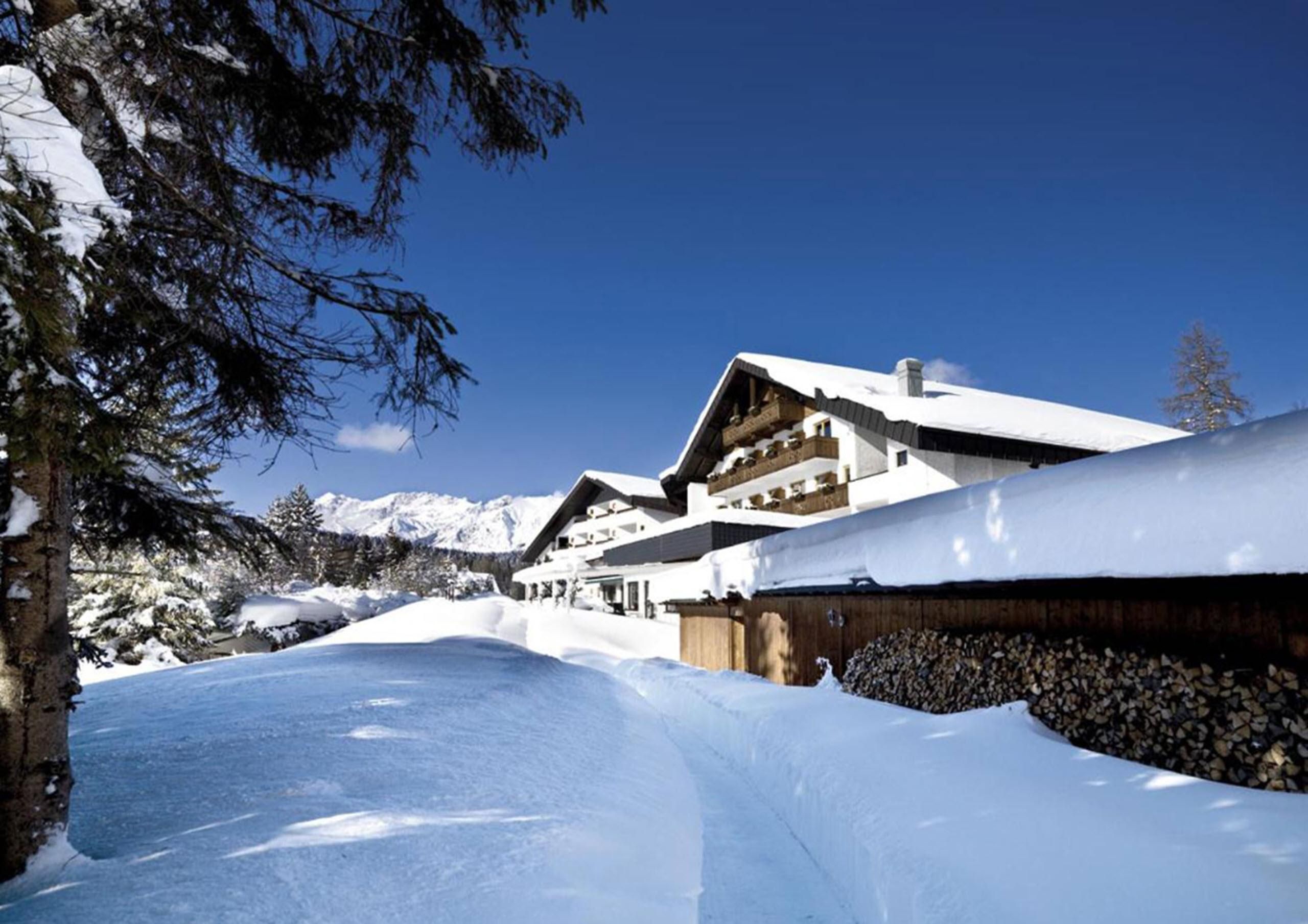 A picturesque chalet in the snow with mountains in the background. The surroundings are covered with fresh, white snow.