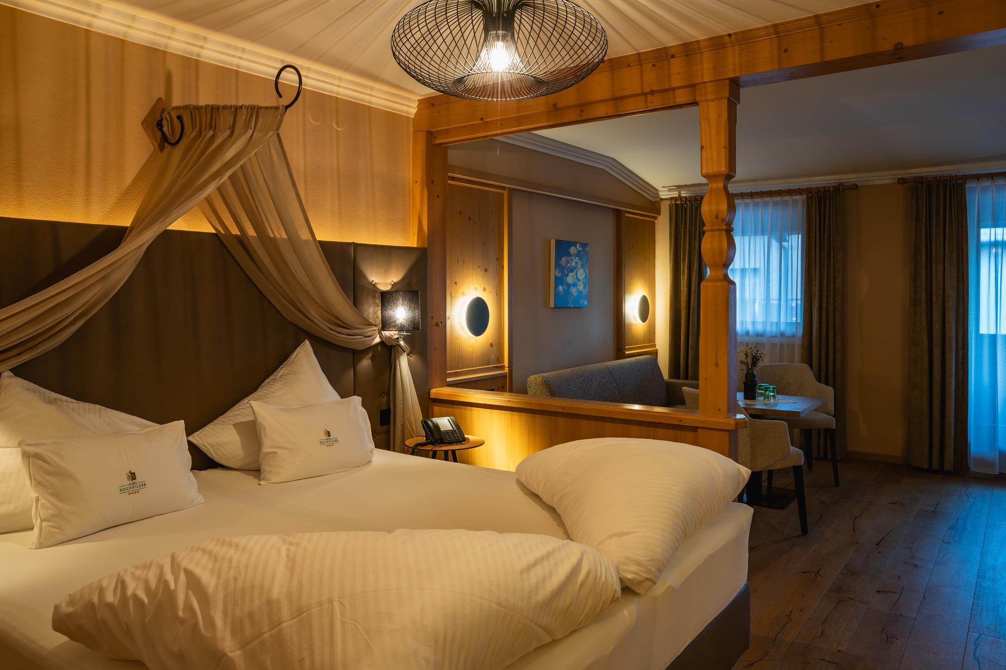 A cozy hotel room with a large bed and elegant decor. The warm colors and beautiful lighting create an inviting atmosphere.