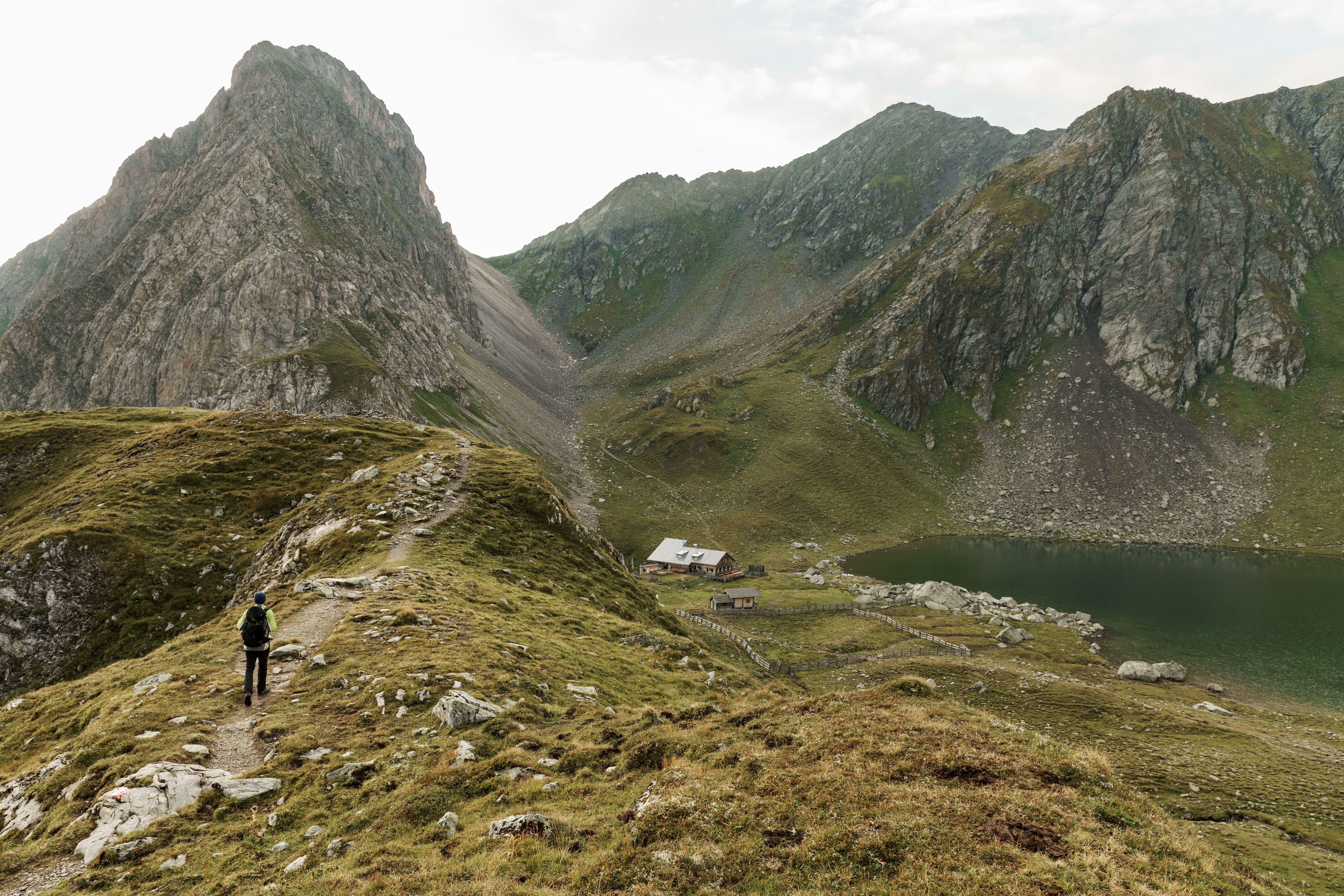 Karnischer Höhenweg, Obstanserseehütte, Wanderer im Gebirge mit Hütte am See