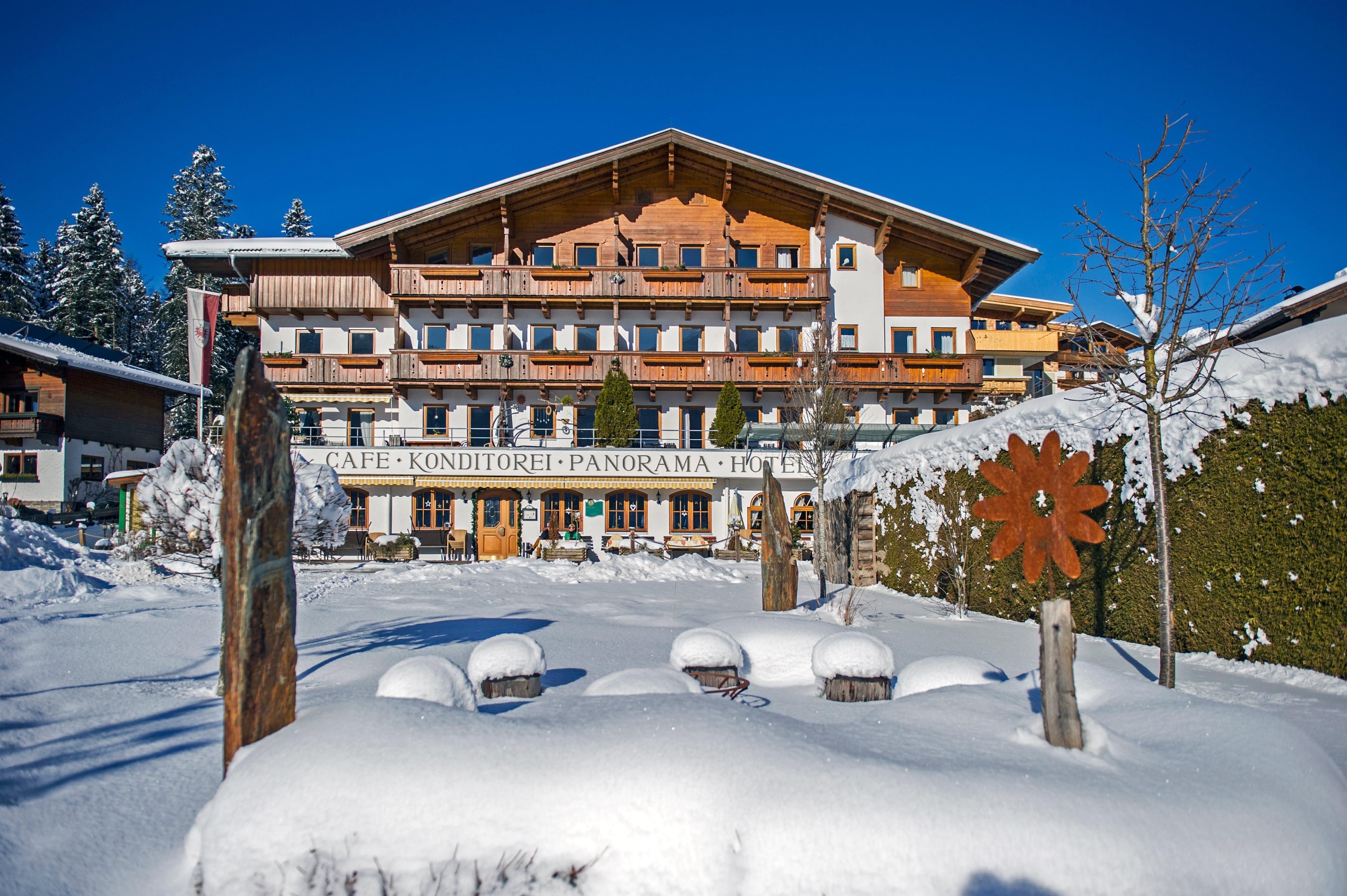 A charming building in Alpine style, surrounded by snow-covered landscapes. The clear blue sky complements the wintry scenery.