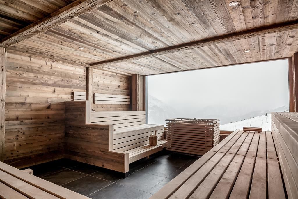 A modern wellness area with wooden paneling and panoramic windows. The room is simply designed and invites relaxation.