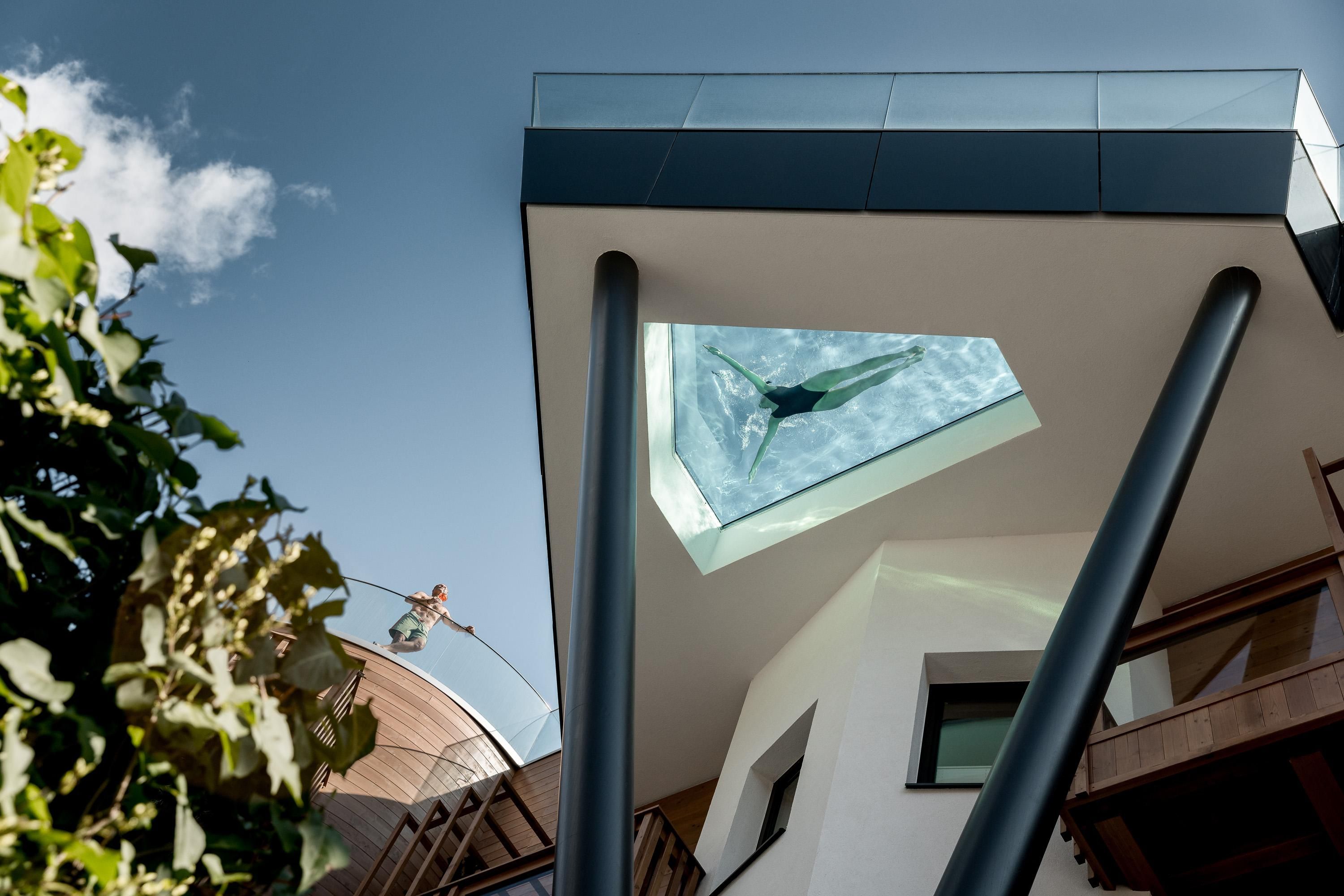 A modern building with a glass skylight. Below, a person can be seen in the water.