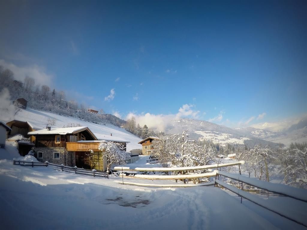 A picturesque winter village with snow-covered houses and a clear blue sky. The surroundings are calm and idyllic.