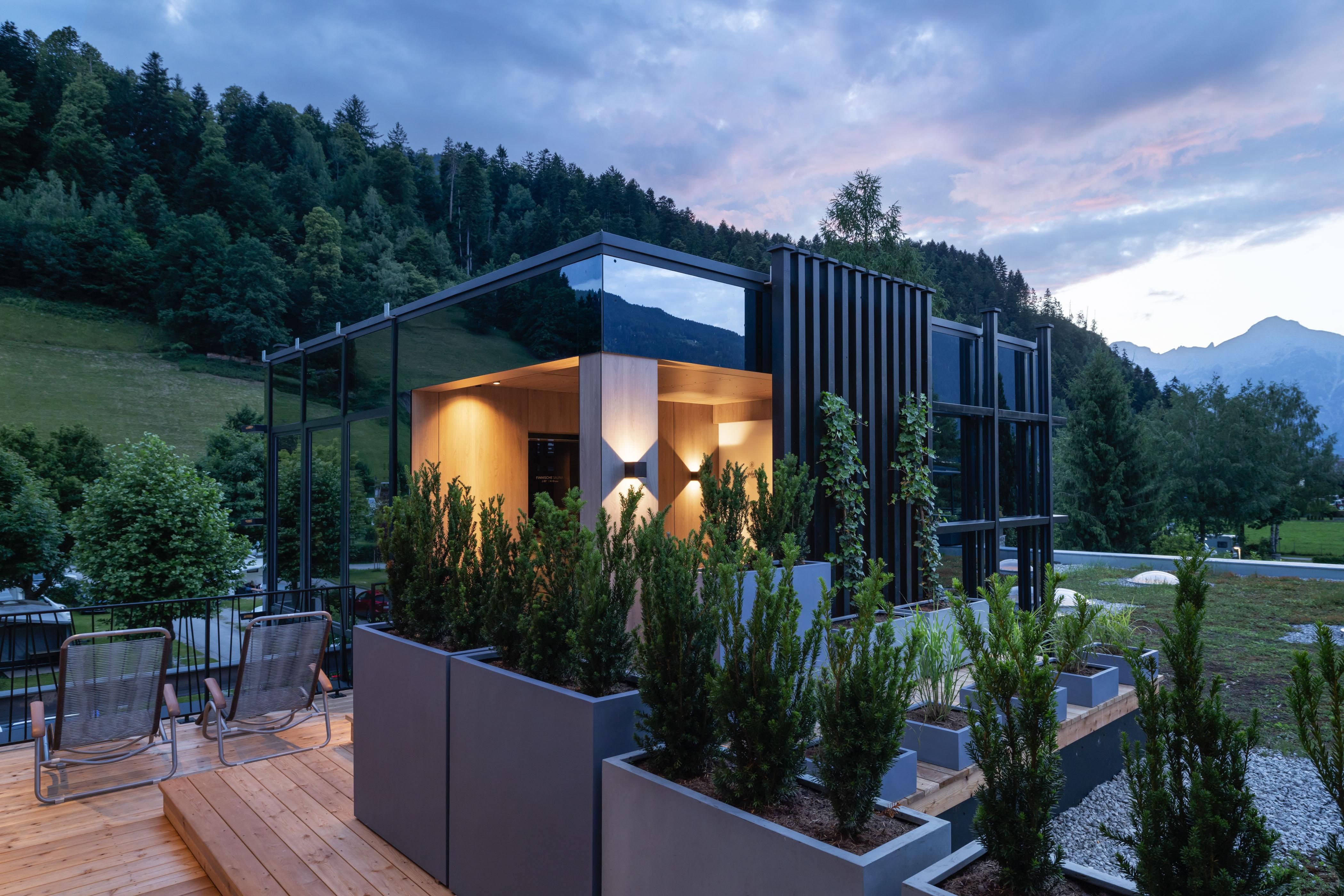 A modern house with large windows and modern architecture. Furthermore, there are garden areas with plants and trees in a landscaped environment.