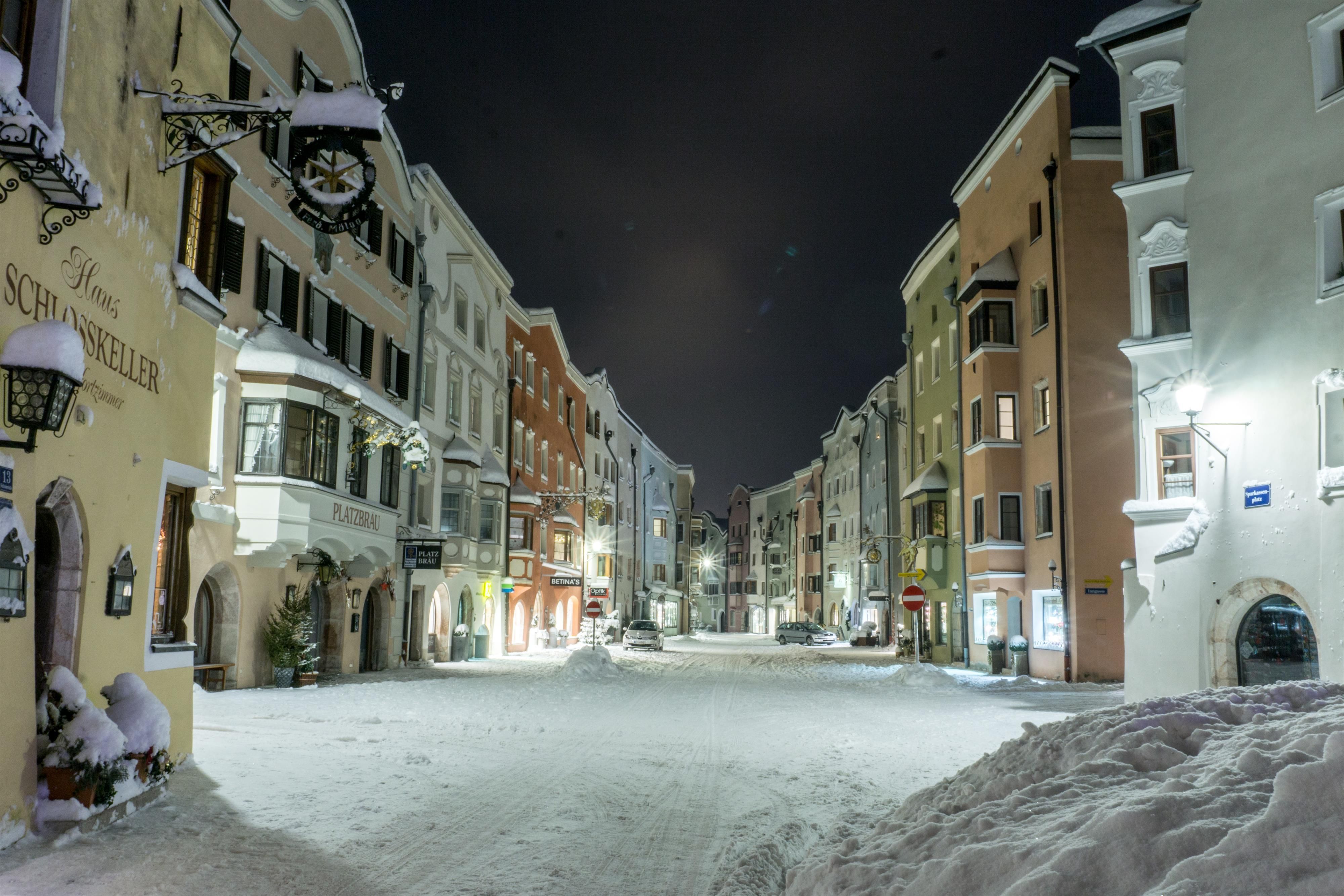 A snowy street view at night with colorful buildings. The atmosphere is calm and inviting.